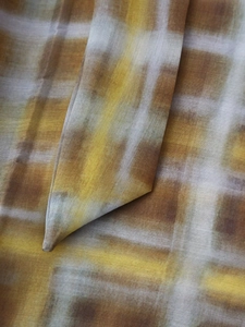 Detailed macro view of sheer yellow and brown abstract plaid fabric texture on the garment