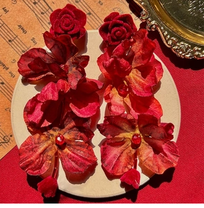 Detailed macro view of large red fabric rose earrings with sparkling rhinestone centers