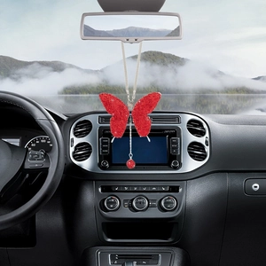 Detail of a red crystal butterfly car pendant hanging on a rearview mirror inside a vehicle