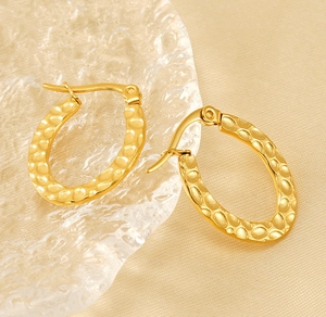 Detailed view of gold oval earrings with hammered texture on silk and glass
