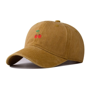 Detail of vintage washed cotton baseball cap with embroidered cherry on mustard fabric