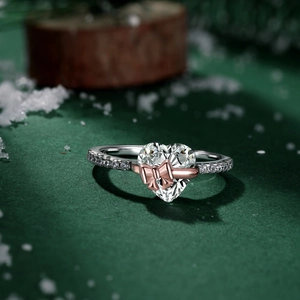 Macro shot of silver ring with heart gemstone, rose gold bow, and pavé set diamonds