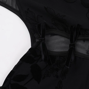 Détail du tissu en maille noire transparente avec flocage floral et nœuds en velours