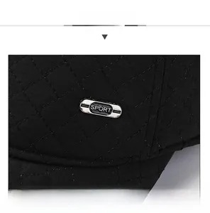Detailed close-up of black quilted diamond stitching and metal Sport badge on the baseball cap
