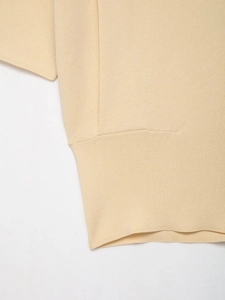 Detail shot of the fine knit texture and stitching on a cream short sleeve top