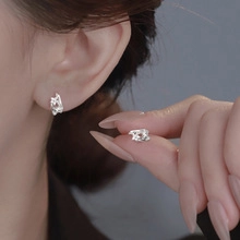 Macro detail of minimalist silver lava-style earring with textured surface on model