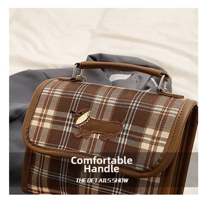 Detail of vintage plaid handbag featuring embroidered dachshund and leather handles