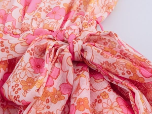 Dettaglio macro del tessuto in chiffon annodato con fiori rosa e arancio stampati
