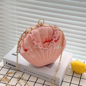 Pink marble shell crossbody bag with golden chain and acrylic handle on vintage props