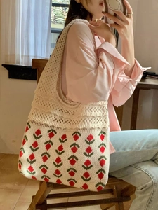 Close-up of cream crochet tote bag with red strawberry pattern and hollow knit texture