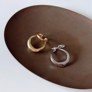 Macro shot of minimalist irregular intertwined silver and gold cuffs on a vintage tray