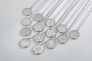 Detailed macro view of various silver hollow circular pendant necklaces with floral patterns