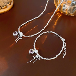 Detail of silver beaded necklace and bracelet with pink hearts and bow pendants
