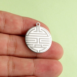 Stainless steel round pendant with Double Happiness engraving held between fingers