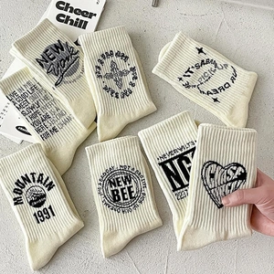 White cotton crew socks for men with black graphic prints and typography in a flat lay