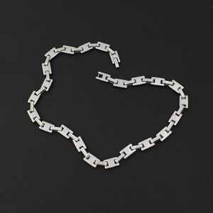 Detail view of silver H-link chain necklace on matte black background showing metallic luster