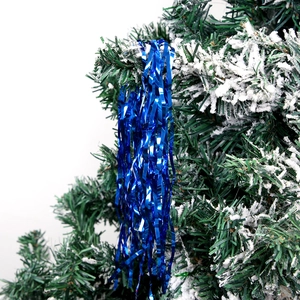 Close-up of blue metallic foil tinsel hanging on a snowy Christmas tree branch