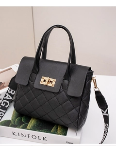 Detail of black quilted handbag with golden twist lock and stylish letter strap