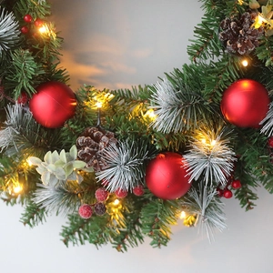 Christmas wreath with red berries, pine cones, and LED lights for door decoration