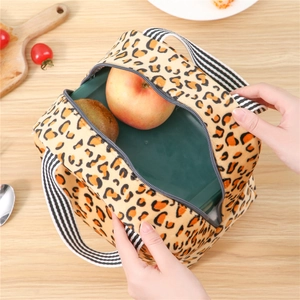 Sac isotherme léopard avec poignées rayées contenant une boîte à lunch et des fruits
