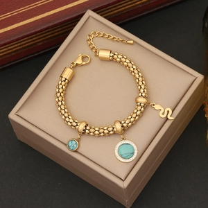 Detail of gold bead chain bracelet with turquoise charms and snake pendant on jewelry box