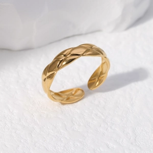 Detailed view of quilted pattern texture on golden stainless steel adjustable open ring