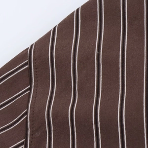 Detailed close-up of brown striped shirt shoulder with refined stitching and cotton texture