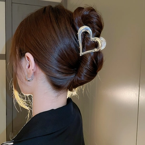 Pince à cheveux en métal argenté en forme de cœur évidé portée par un mannequin élégant