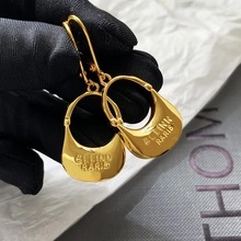 Macro shot of gold-plated mini hobo bag earrings with elegant polished finish