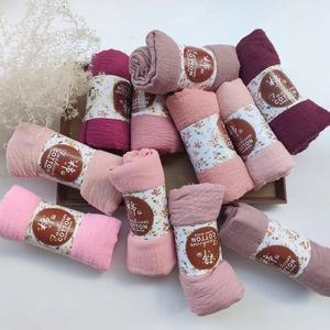 Detailed texture of pleated cotton viscose scarves with vintage labels on wooden tray