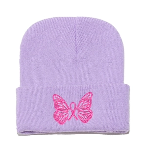Dettaglio del ricamo a farfalla rosa su un berretto in maglia viola lavanda per l'inverno