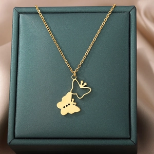 Detail of 18k gold butterfly necklace on green jewelry box and champagne silk backdrop