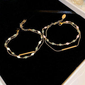 Detail of double-layer gold plated bracelet with multi-colored beads on black velvet