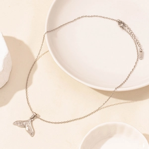 Detail of silver whale tail pendant with vintage sea textures and lobster clasp chain