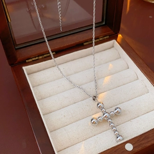 Vue détaillée d'un pendentif croix argenté avec perles sur chaîne torsadée en boîte bois