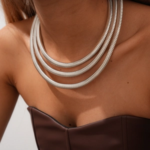 Detailed view of elegant silver-tone triple-layer snake chains on model's neck