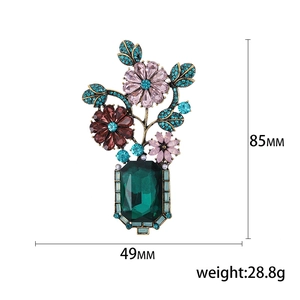 Vintage Baroque floral brooch with green gemstone and colorful rhinestones on white background