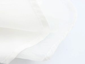 Nahaufnahme der weißen Jacquard-Stoffstruktur und feinen Nähte am sommerlichen Kleid