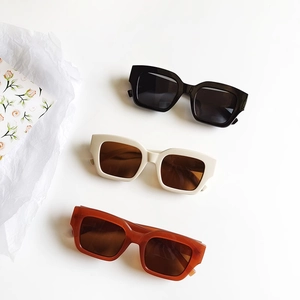 Retro square frame sunglasses in black, beige, and amber brown colors on a white surface