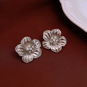 Macro view of silver flower earrings with zircon center on textured background