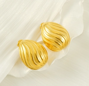 Macro detail of gold-plated oval stud earrings featuring an elegant spiral texture design