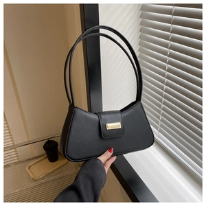 Detail of black matte baguette bag featuring a gold rectangular buckle and shadow lighting