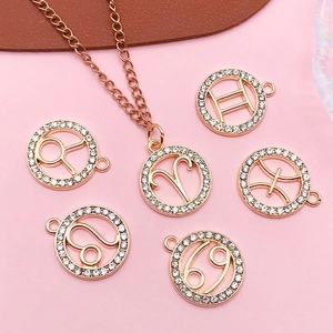 Macro view of rose gold zodiac pendants with crystals on a pink background