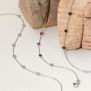 Three minimalist stainless steel necklaces with round colorful, clear, and black gemstones