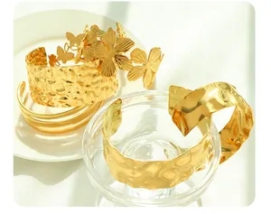 Detail of gold-plated open bangles featuring unique hammered textures and floral butterfly accents