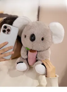 Close-up of a soft grey koala plush toy holding a pink cylinder in a home setting