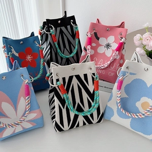 Multiple knitted handbags with colorful patterns and braided rope handles in a group set
