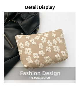 Detail of khaki cosmetic bag featuring white 3D floral embroidery and zipper closure