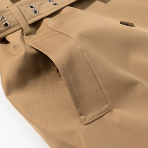 Detailed close-up of khaki trench coat fabric texture with belt eyelets and stitching