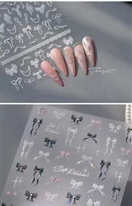 Macro view of 3D iridescent ribbon and pearl nail stickers on long almond nails
